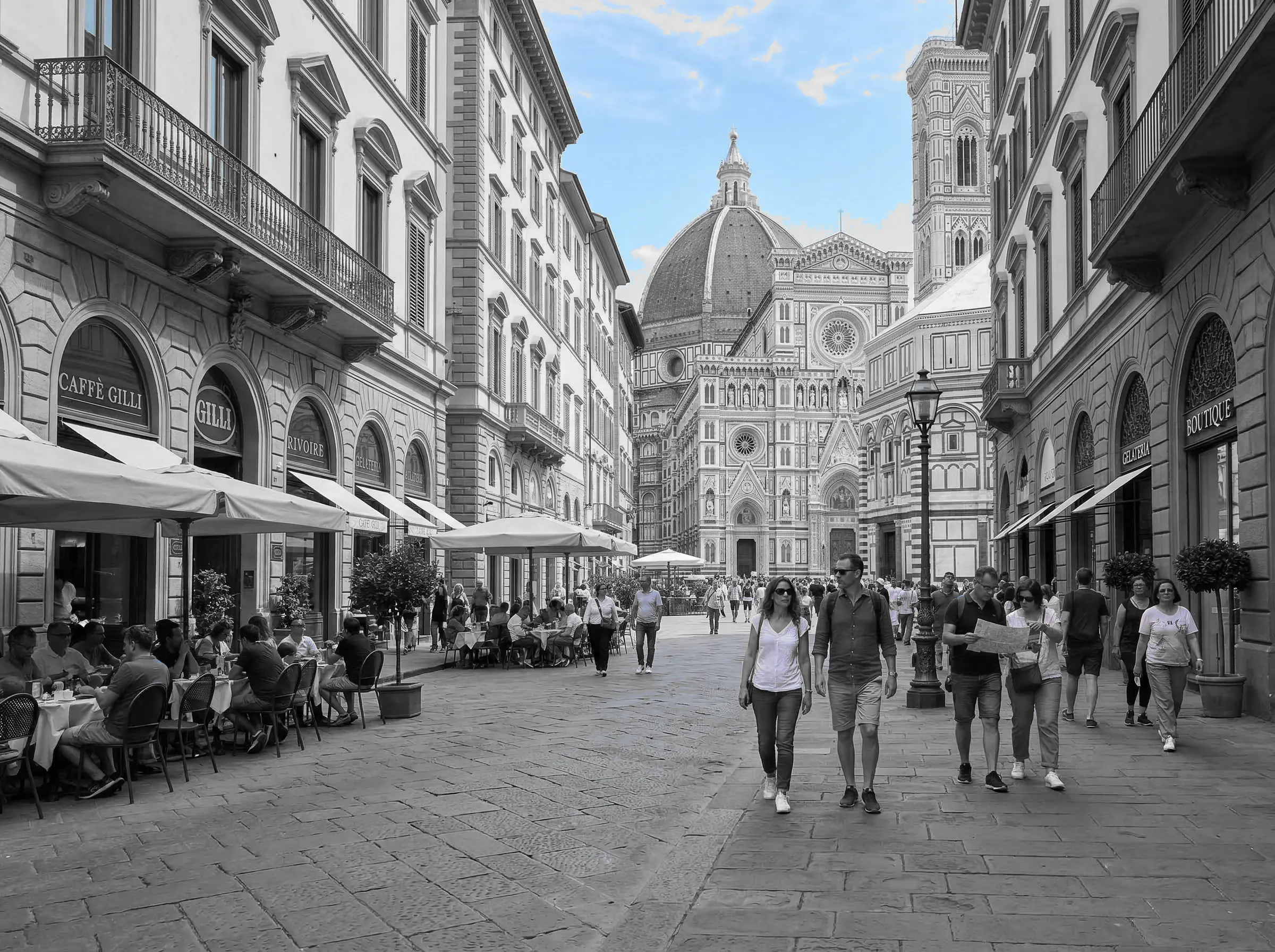 Historic street scene with the blue sky preserved while buildings and people shift to grayscale